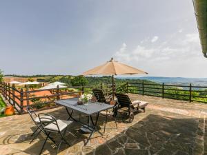 a patio with a table and chairs and an umbrella at Holiday Home Ciliegiolo by Interhome in Cinigiano