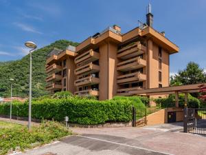 ein großes Gebäude mit Büschen vor einem Parkplatz in der Unterkunft Apartment Gaggetto by Interhome in Laveno-Mombello
