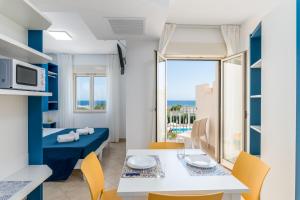 sala de estar con mesa, sillas y cama en Calanca Apulian Residence, en Torre Santa Sabina