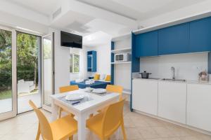 a kitchen with blue cabinets and a white table and chairs at Calanca Apulian Residence in Torre Santa Sabina