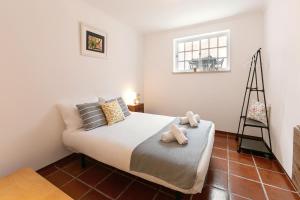 1 dormitorio con 1 cama con silla y ventana en Villa Juno, en Atouguia da Baleia
