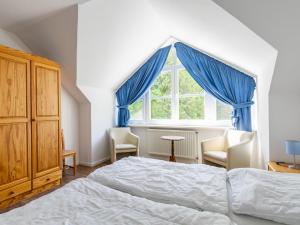 een slaapkamer met een bed en een raam met blauwe gordijnen bij Holiday Home Losentitz by Interhome in Losentitz
