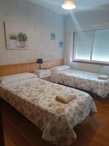 a room with two beds and a window at Albergue Camiño Real in Sigüeiro