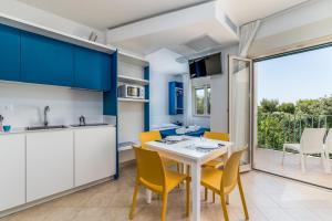 a kitchen and dining room with a white table and yellow chairs at Calanca Apulian Residence in Torre Santa Sabina