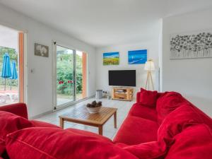 ein Wohnzimmer mit einem roten Sofa und einem TV in der Unterkunft Holiday Home Les Acacias - MVT245 by Interhome in Vendays-Montalivet