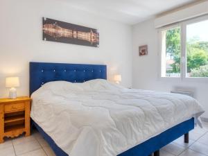 a bedroom with a large bed with a blue headboard at Holiday Home Les Acacias - MVT245 by Interhome in Vendays-Montalivet