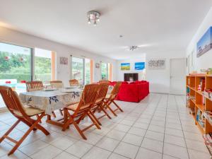 ein Esszimmer mit einem Tisch, Stühlen und einem roten Sofa in der Unterkunft Holiday Home Les Acacias - MVT245 by Interhome in Vendays-Montalivet