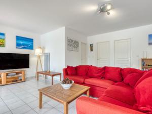 ein Wohnzimmer mit einem roten Sofa und einem TV in der Unterkunft Holiday Home Les Acacias - MVT245 by Interhome in Vendays-Montalivet