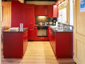 cocina con armarios rojos y encimera negra en Apartment Argentière 8 by Interhome, en Villars-sur-Ollon