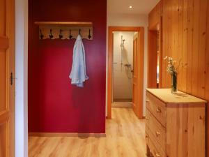 Un baño con una pared roja con una bata blanca. en Apartment Argentière 8 by Interhome, en Villars-sur-Ollon