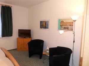 ヴァーネミュンデにあるHaus Seewind Warnemuende _ Objektのデスク、椅子2脚、テレビが備わる客室です。
