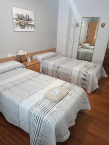 two beds in a room with a mirror at Albergue Camiño Real in Sigüeiro