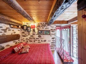 a bedroom with a red bed in a room with a stone wall at Chalet Il Gianlupo by Interhome in Bognanco
