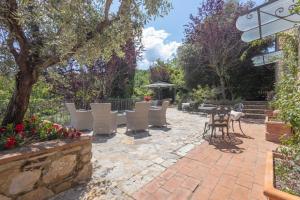 a patio with chairs and tables and a tree at Il Casello Country House in Greve in Chianti