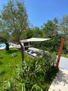 un jardín con una mesa y una sombrilla blanca en Wellness House Oliva with heated salt water Pool, Sauna & Jakuzzi en Labin