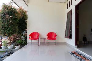 2 rote Stühle und ein Tisch auf einer Veranda in der Unterkunft RedDoorz At Pariban Homestay Parbaba in Sinabono