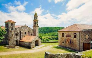 un antiguo edificio de piedra con una torre y una iglesia en Monasterio y Pensión de Moraime, en Muxía