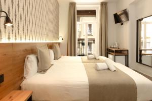 a bedroom with a large bed with white sheets and pillows at Hotel La Milagrosa in Alicante