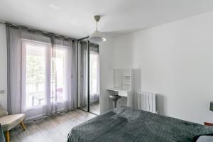 a white bedroom with a bed and a window at Le Long du Fleuve - Appt avec balcon vue fleuve in Saint-André-de-Cubzac