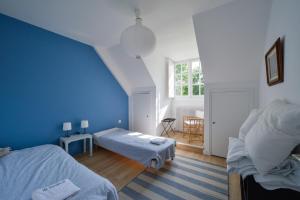 1 dormitorio con 2 camas y pared azul en La Genêtière - Grande maison avec étang en Sologne en Méry-ès-Bois