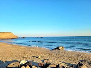 a sandy beach with rocks and the ocean at Bel appartement sur le port avec jardin in Cap d'Agde