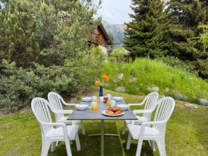 a table with white chairs and food on it at Chalet Biquinou by Interhome in Verbier