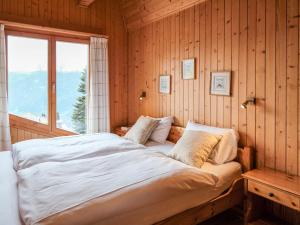 a bed in a wooden room with a window at Chalet Biquinou by Interhome in Verbier