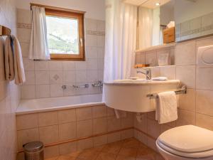 La salle de bains est pourvue d'un lavabo, d'une baignoire et de toilettes. dans l'établissement Apartment Allegra Sur 201 by Interhome, à Zuoz