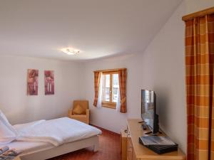 Schlafzimmer mit einem Bett, einem TV und einem Stuhl in der Unterkunft Apartment Allegra Sur 201 by Interhome in Zuoz