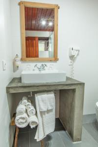 a bathroom with a sink and a pile of towels at Aldeia da Cuada in Faja Grande