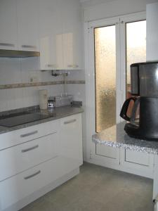 cocina con armarios blancos, fregadero y microondas en Suances Costa Quebrada en Suances