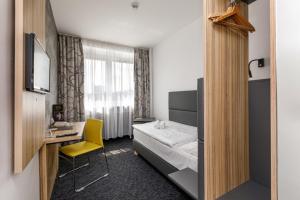 a bedroom with a bed and a desk and a yellow chair at Harmony Club Hotel in Ostrava
