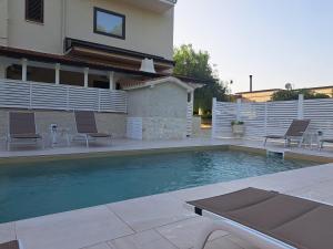 una piscina con 2 sillas y una casa en Il Piccolo Principe Relais, en Villapiana