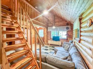 - un salon avec un canapé et des escaliers dans une cabane en rondins dans l'établissement Holiday Home Kaakonranta by Interhome, à Kinnula