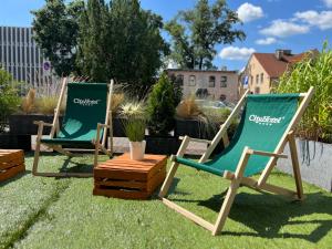 zwei grüne Gartenstühle auf dem Rasen in der Unterkunft City Hotel in Bydgoszcz