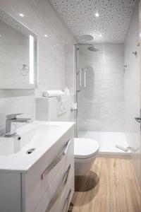 a white bathroom with a toilet and a shower at Logis Hotel Le Provencal in Les Issambres