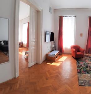 a living room with a couch and a television on a hard wood floor at Citypark Classic Downtown Apartment in Budapest