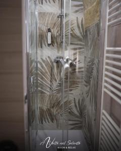 d'une douche avec une porte en verre et une fresque murale. dans l'établissement AvVolta nel Salento - Room & Relax, à Torchiarolo