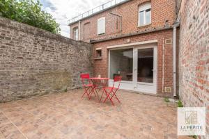 un patio con sillas rojas y una mesa junto a una pared de ladrillo en Residence Poterne en Valenciennes