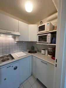 cocina con armarios blancos, fregadero y microondas en Apartment Pegase Phenix-62 by Interhome, en Le Corbier