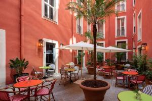 un patio al aire libre con mesas, sillas y una palmera en UNAHOTELS Trastevere Roma, en Roma