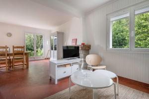 a living room with a television and a table and chairs at Détente au calme et près de la plage in Saint-Gildas-de-Rhuys