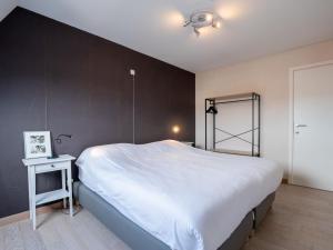 ブレーデネにあるApartment Residentie Zandloper II by Interhomeの白い大型ベッドと黒い壁のベッドルーム1室