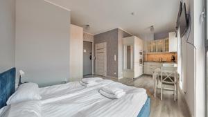 duże białe łóżko w pokoju z kuchnią w obiekcie Apartamenty Sun & Snow Deo Plaza Granaria w Gdańsku