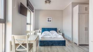 um pequeno quarto com uma cama, uma mesa e cadeiras em Apartamenty Sun & Snow Deo Plaza Granaria em Gdańsk