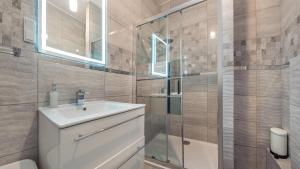 a bathroom with a sink and a glass shower at Apartamenty Sun & Snow Deo Plaza Granaria in Gdańsk