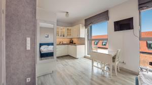 a kitchen with white cabinets and a desk in a room at Apartamenty Sun & Snow Deo Plaza Granaria in Gdańsk
