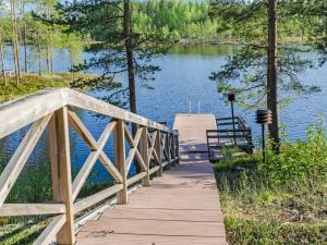eine Holzbrücke über einen See mit einer Bank in der Unterkunft Holiday Home Papulantupa by Interhome in Kulho