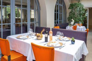 a table with a white table cloth and wine bottles at Logis Hôtel le Provencal Rest les Mûriers in Les Issambres
