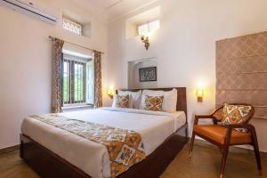 a bedroom with a large bed and a chair at Kanak Vilas by StayVista, a Rajasthani haveli boutique stay with hill views, offering both indoor and outdoor games for a delightful retreat in Jaipur